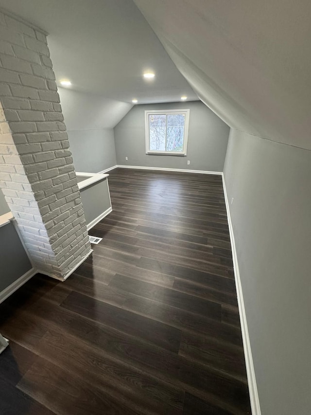 bonus room with lofted ceiling, baseboards, and dark wood-type flooring