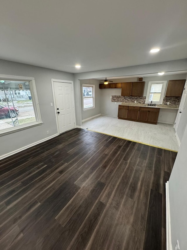 interior space with a sink, dark wood-type flooring, backsplash, and baseboards