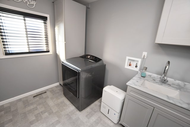 laundry room featuring washer / clothes dryer, cabinet space, a sink, and baseboards