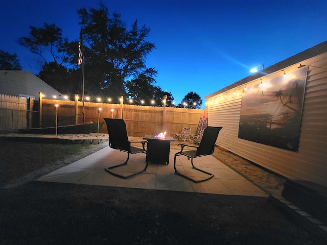 patio at night with a fire pit and fence