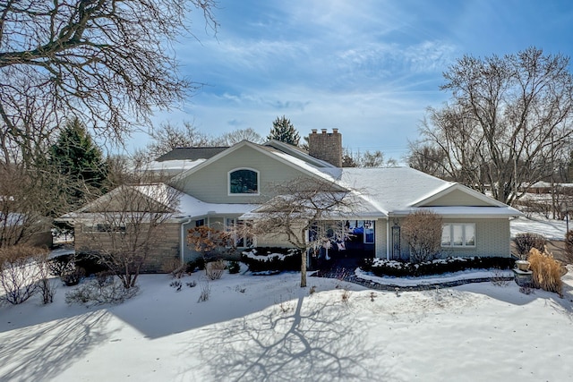 view of front facade with a chimney and brick siding