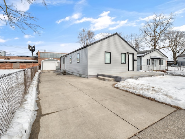 view of property exterior featuring concrete driveway, an outdoor structure, a detached garage, and fence