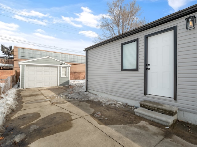 exterior space featuring driveway, a detached garage, and fence