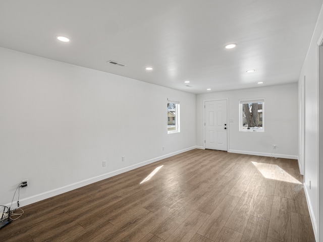 empty room featuring dark wood-style flooring, visible vents, and baseboards