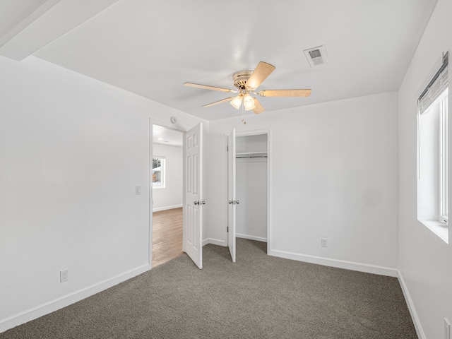 unfurnished bedroom with baseboards, visible vents, a ceiling fan, carpet floors, and a closet