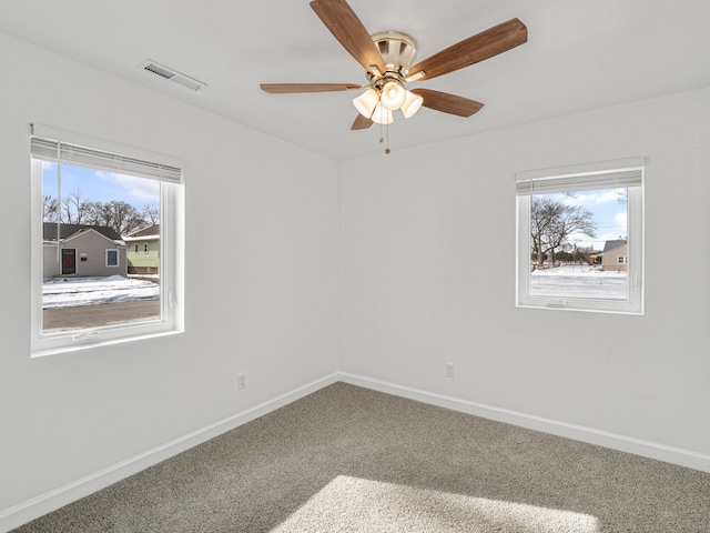 empty room with carpet floors, visible vents, baseboards, and a ceiling fan