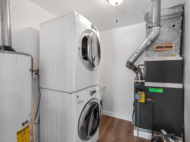 washroom with laundry area, dark wood-type flooring, stacked washer and dryer, baseboards, and water heater