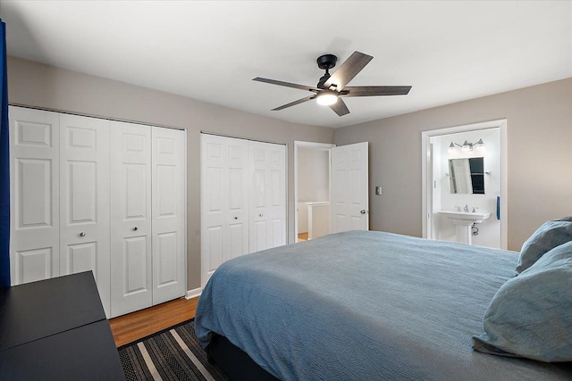 bedroom with ceiling fan, wood finished floors, ensuite bath, and two closets