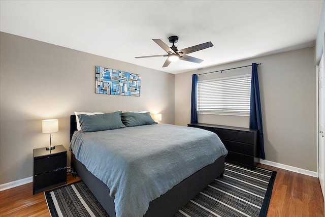 bedroom with ceiling fan, wood finished floors, and baseboards