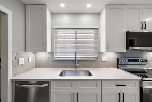 kitchen with tasteful backsplash, white cabinets, appliances with stainless steel finishes, light countertops, and a sink