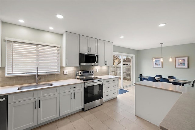 kitchen with decorative backsplash, appliances with stainless steel finishes, light countertops, and a sink