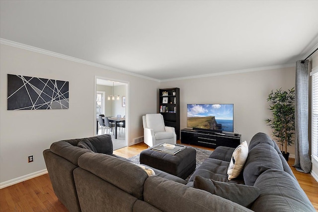 living area featuring ornamental molding, baseboards, visible vents, and light wood finished floors