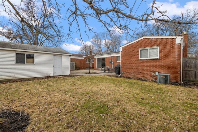 rear view of house with a lawn, a patio, fence, central air condition unit, and brick siding