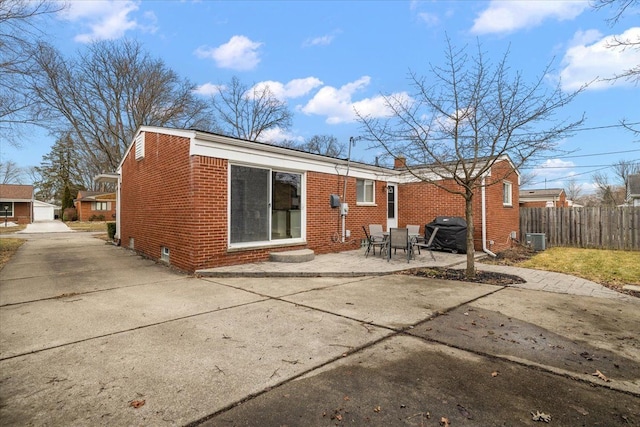 rear view of house featuring central AC unit, a patio area, fence, and brick siding