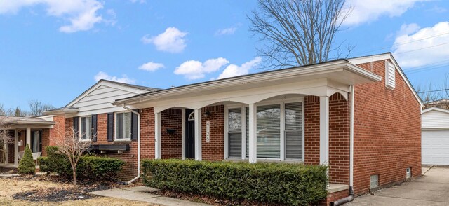 view of front of home with an outbuilding, driveway, brick siding, and a garage