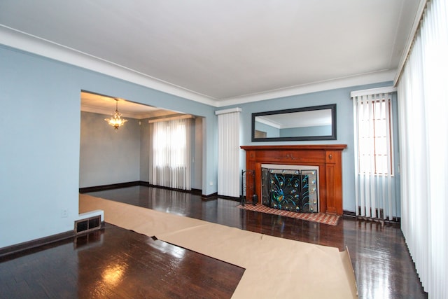 unfurnished living room with visible vents, an inviting chandelier, a fireplace with flush hearth, wood finished floors, and baseboards