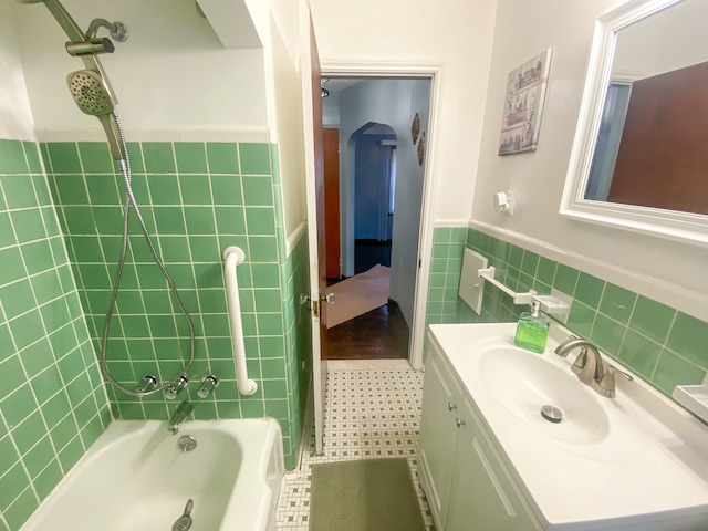 bathroom featuring a wainscoted wall, vanity, bathtub / shower combination, and tile walls