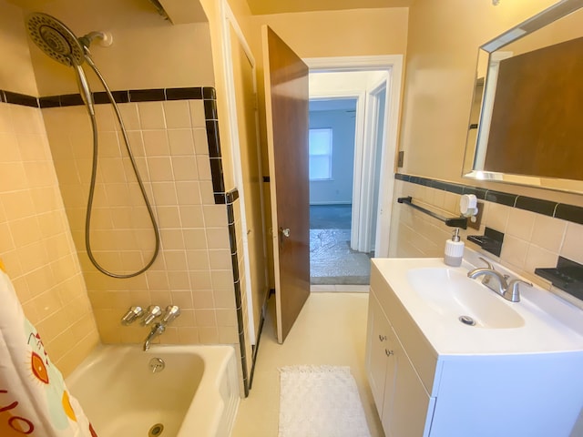 full bathroom featuring a wainscoted wall, vanity, shower / bath combo with shower curtain, and tile walls