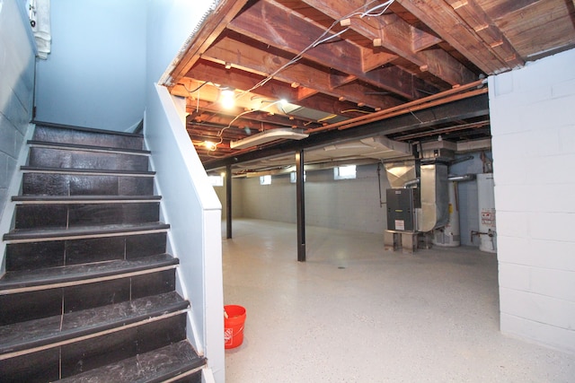 below grade area featuring water heater, stairway, and heating unit