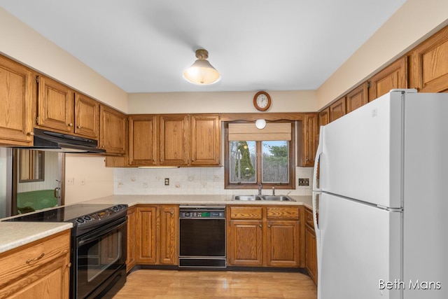 kitchen featuring black appliances, brown cabinets, a sink, and under cabinet range hood