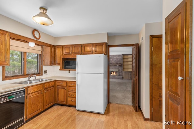 kitchen with black appliances, light countertops, a sink, and brown cabinetry