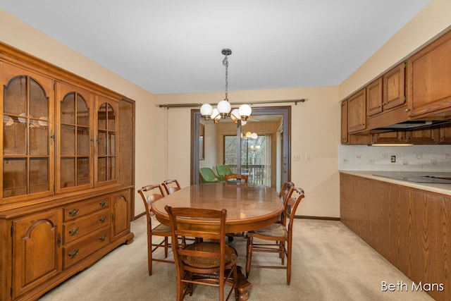 dining area with light colored carpet, baseboards, and an inviting chandelier