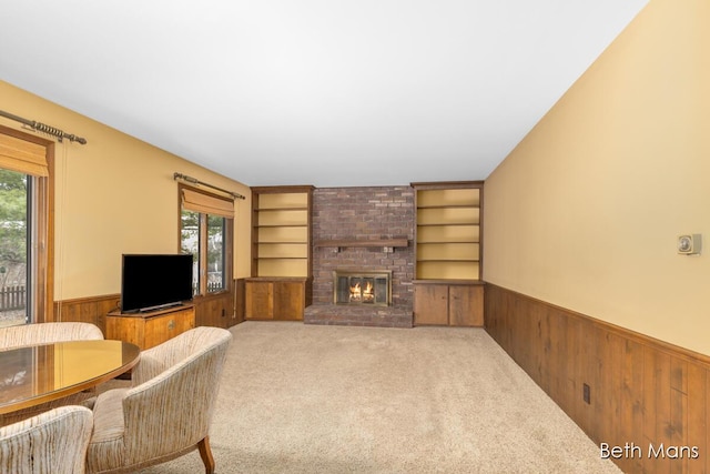 living area with a healthy amount of sunlight, a wainscoted wall, built in shelves, and wood walls