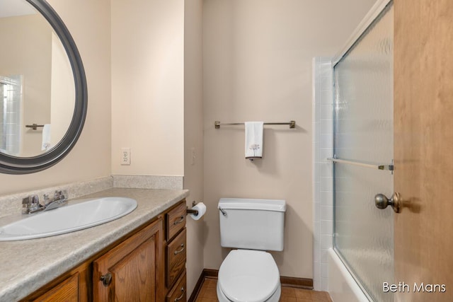 bathroom featuring combined bath / shower with glass door, vanity, toilet, and baseboards