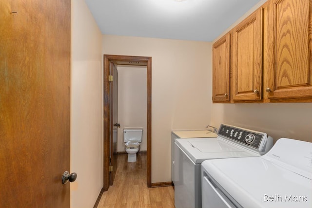 laundry area featuring light wood-type flooring, cabinet space, and washing machine and dryer