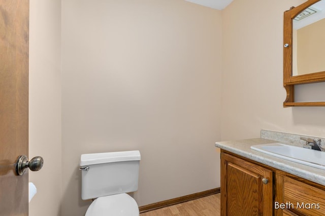 bathroom with wood finished floors, vanity, toilet, and baseboards