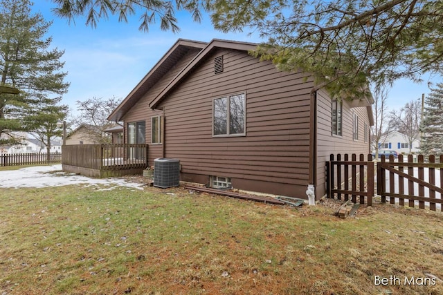 view of side of property with central air condition unit, a lawn, a wooden deck, and fence