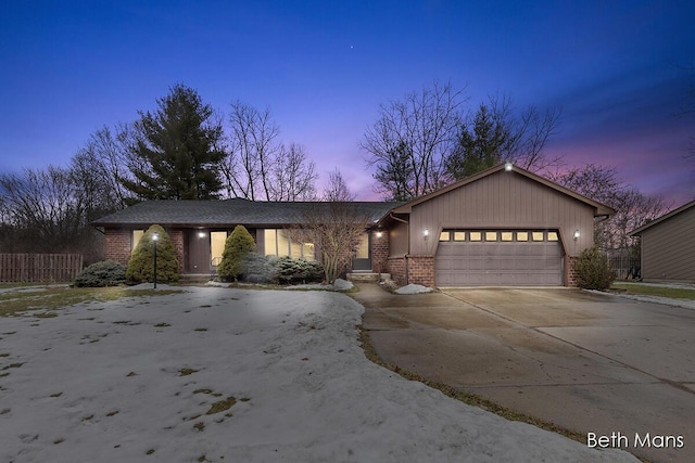 view of front of home with a garage, concrete driveway, brick siding, and fence