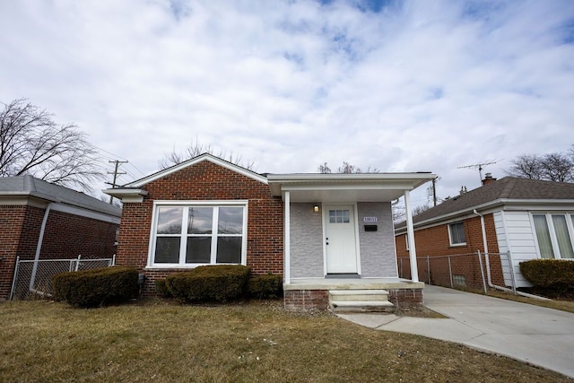 bungalow-style home with fence, a front lawn, and brick siding