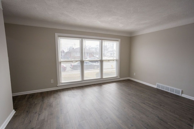 unfurnished room featuring dark wood-type flooring, visible vents, and baseboards