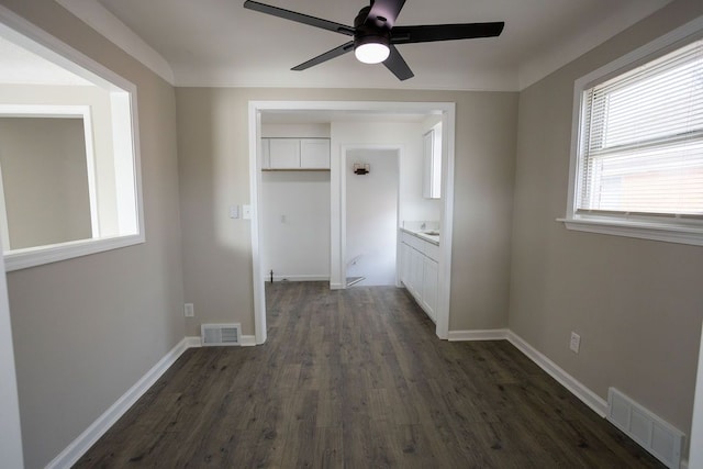 interior space with dark wood-style flooring, visible vents, and baseboards