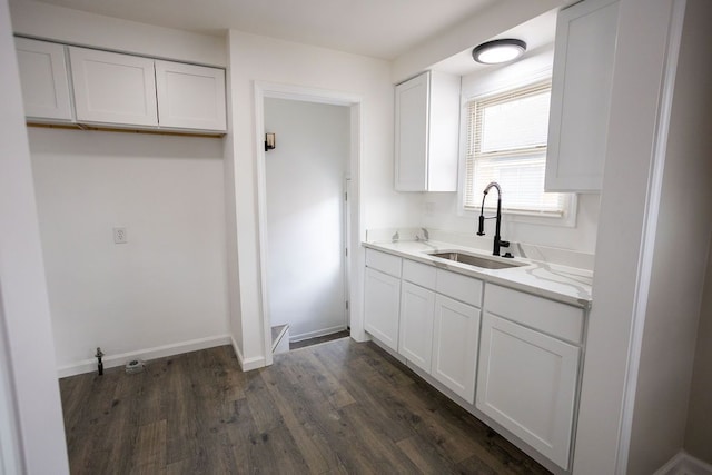 kitchen featuring a sink, white cabinetry, baseboards, light countertops, and dark wood-style floors