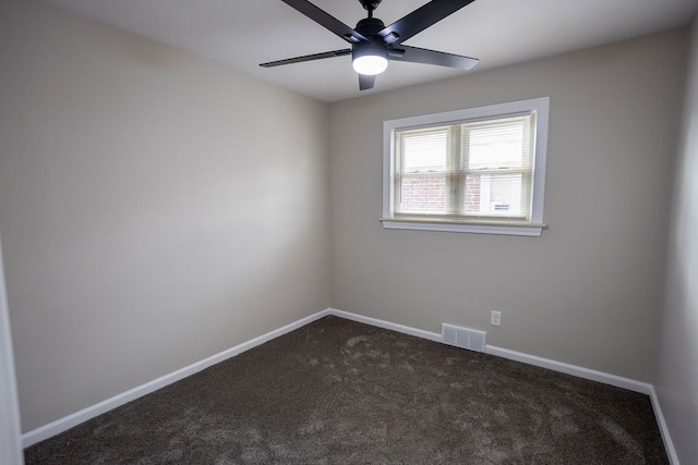 spare room featuring dark colored carpet, visible vents, ceiling fan, and baseboards