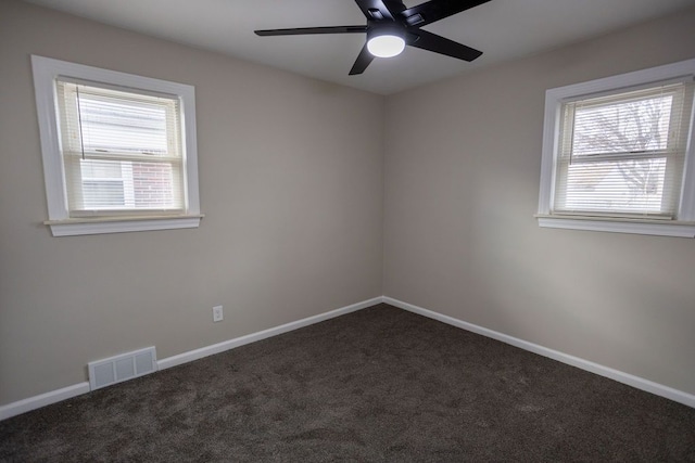 unfurnished room with a wealth of natural light, carpet flooring, visible vents, and baseboards