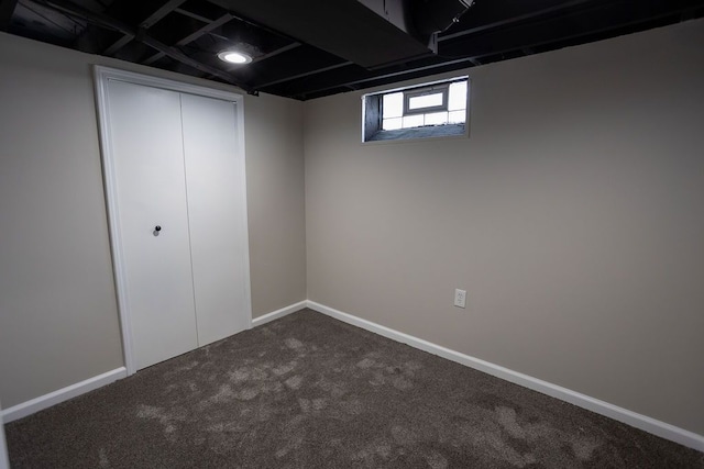 basement with dark colored carpet and baseboards