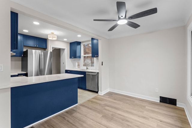 kitchen with visible vents, stainless steel appliances, light countertops, blue cabinetry, and a sink