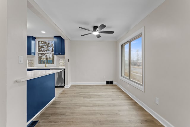 kitchen featuring blue cabinetry, a wealth of natural light, light countertops, visible vents, and stainless steel dishwasher