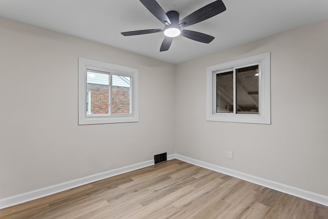 empty room featuring ceiling fan, light wood finished floors, visible vents, and baseboards