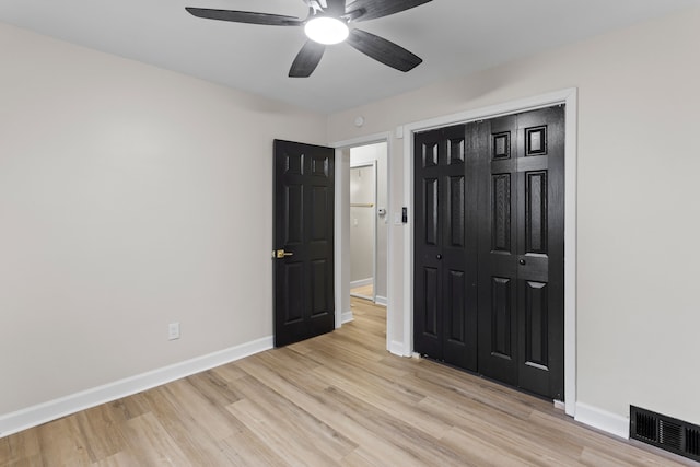 unfurnished bedroom featuring light wood-style flooring, a closet, visible vents, and baseboards