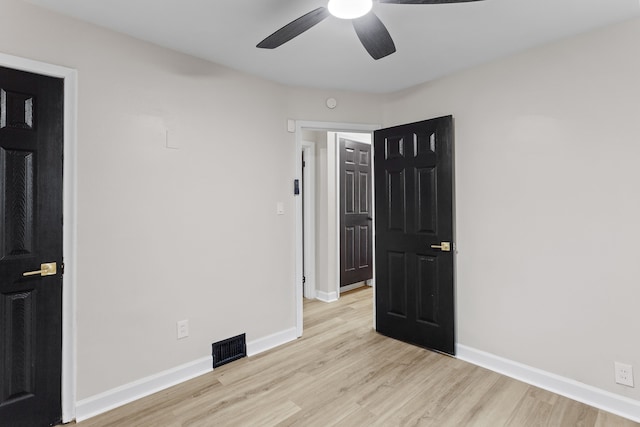 unfurnished room featuring light wood-style floors, baseboards, visible vents, and ceiling fan