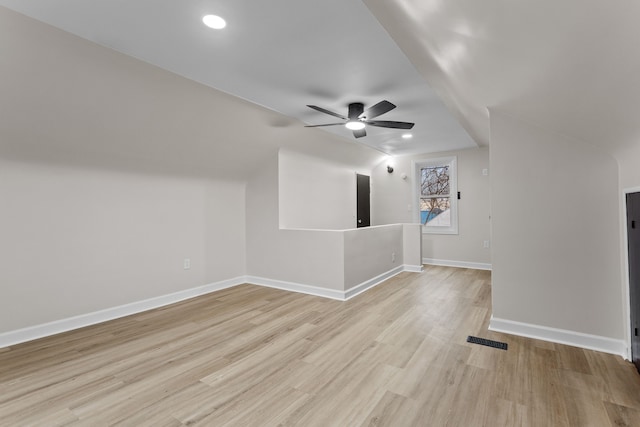 interior space featuring wood finished floors, visible vents, a ceiling fan, vaulted ceiling, and baseboards