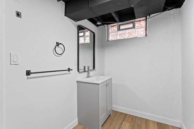 interior space featuring vanity, wood finished floors, a wealth of natural light, and baseboards