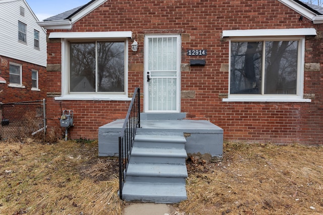 entrance to property with brick siding and fence