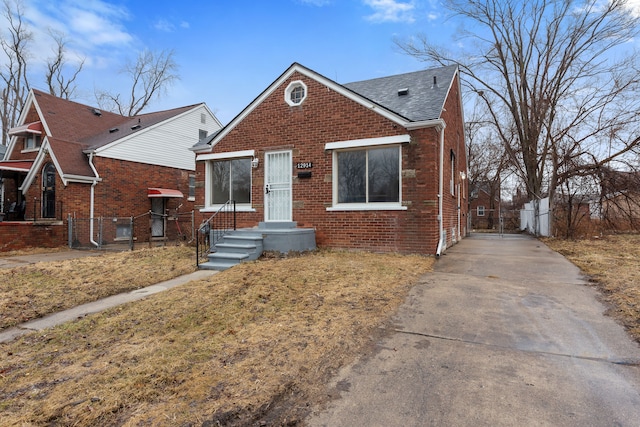 bungalow-style house featuring brick siding, a shingled roof, and fence