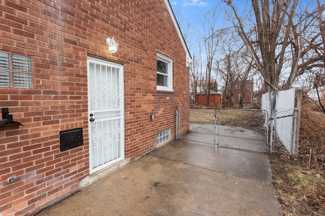 property entrance featuring a gate, brick siding, and fence