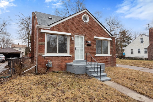 bungalow-style house featuring a shingled roof, fence, and brick siding